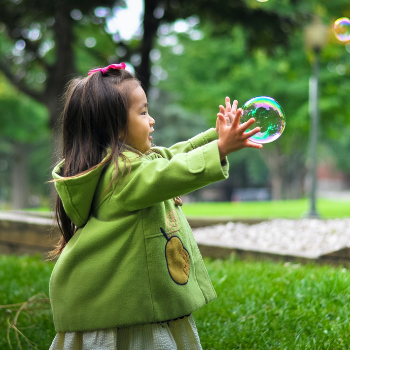 Oriental Girl playing with bubbles in a park