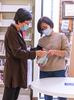 two asian women looking at books in the library